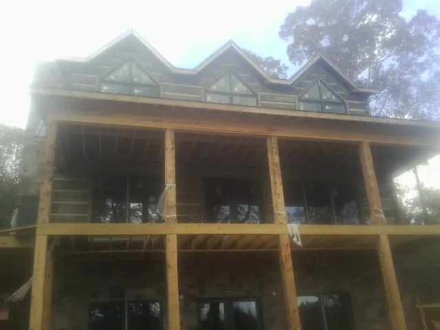 Dormers and porch framing on a large log home under construction — Roof Coating work by our crew in Seth