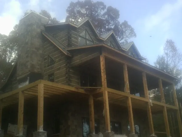 Stone chimney and dormers on a large log home with a timber porch in Seth