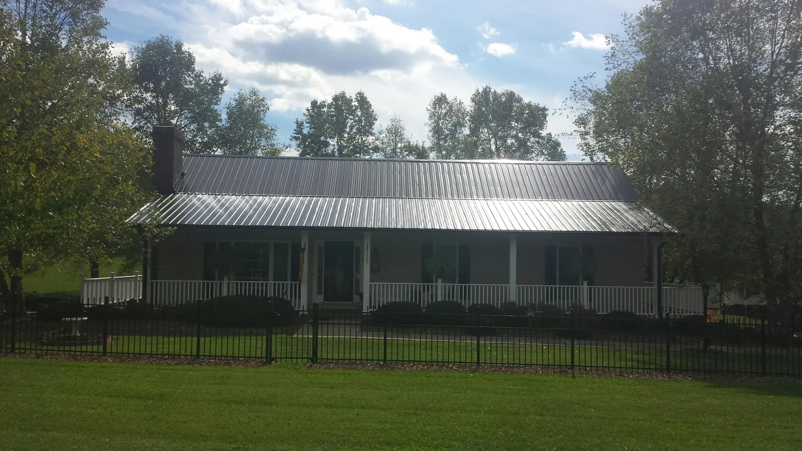 Gray metal roof on a brick ranch with a full width front porch — Gutter Guard Installation work by our crew in Seth