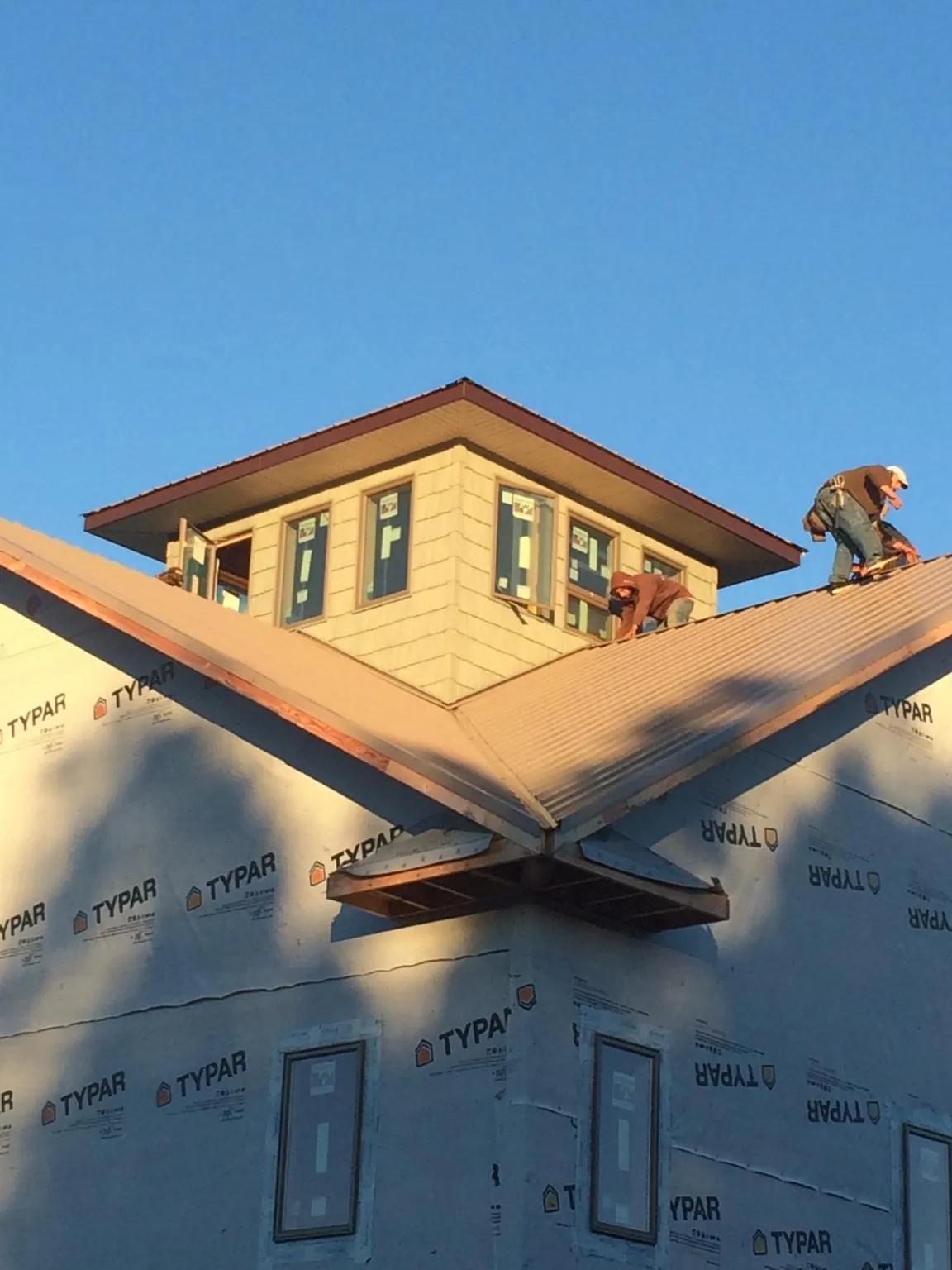 Roofers working around a rooftop cupola on a new metal roof at sunset — Roof Waterproofing in Seth by Roofing Brothers